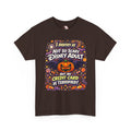 A brown short-sleeve crewneck t-shirt with a colorful graphic print on the front. The graphic features a jack-o'-lantern, bats, candy corn, and fireworks, with the text 'I IDENTIFY AS NOT SO SCARY DISNEY ADULT BUT MY CREDIT CARD IS TERRIFIED!' in stylized fonts.