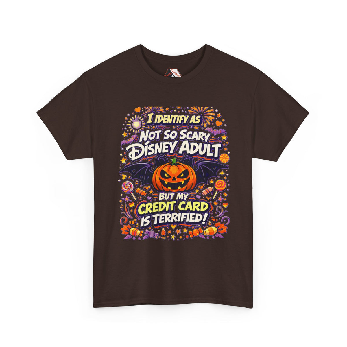 A brown short-sleeve crewneck t-shirt with a colorful graphic print on the front. The graphic features a jack-o'-lantern, bats, candy corn, and fireworks, with the text 'I IDENTIFY AS NOT SO SCARY DISNEY ADULT BUT MY CREDIT CARD IS TERRIFIED!' in stylized fonts.