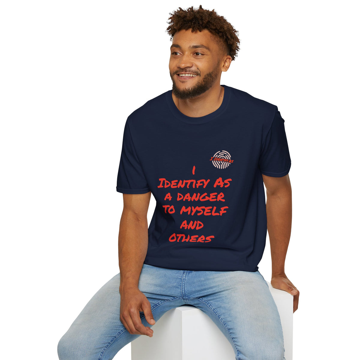 Man wearing a navy blue t-shirt with colorful graphics sitting on a white stool against a white background. 'I IDENTIFY AS A DANGER TO MYSELF AND OTHERS’ in a bold stacked font, with the I Identify As™ circular fingerprint logo printed above the text on the left chest.
