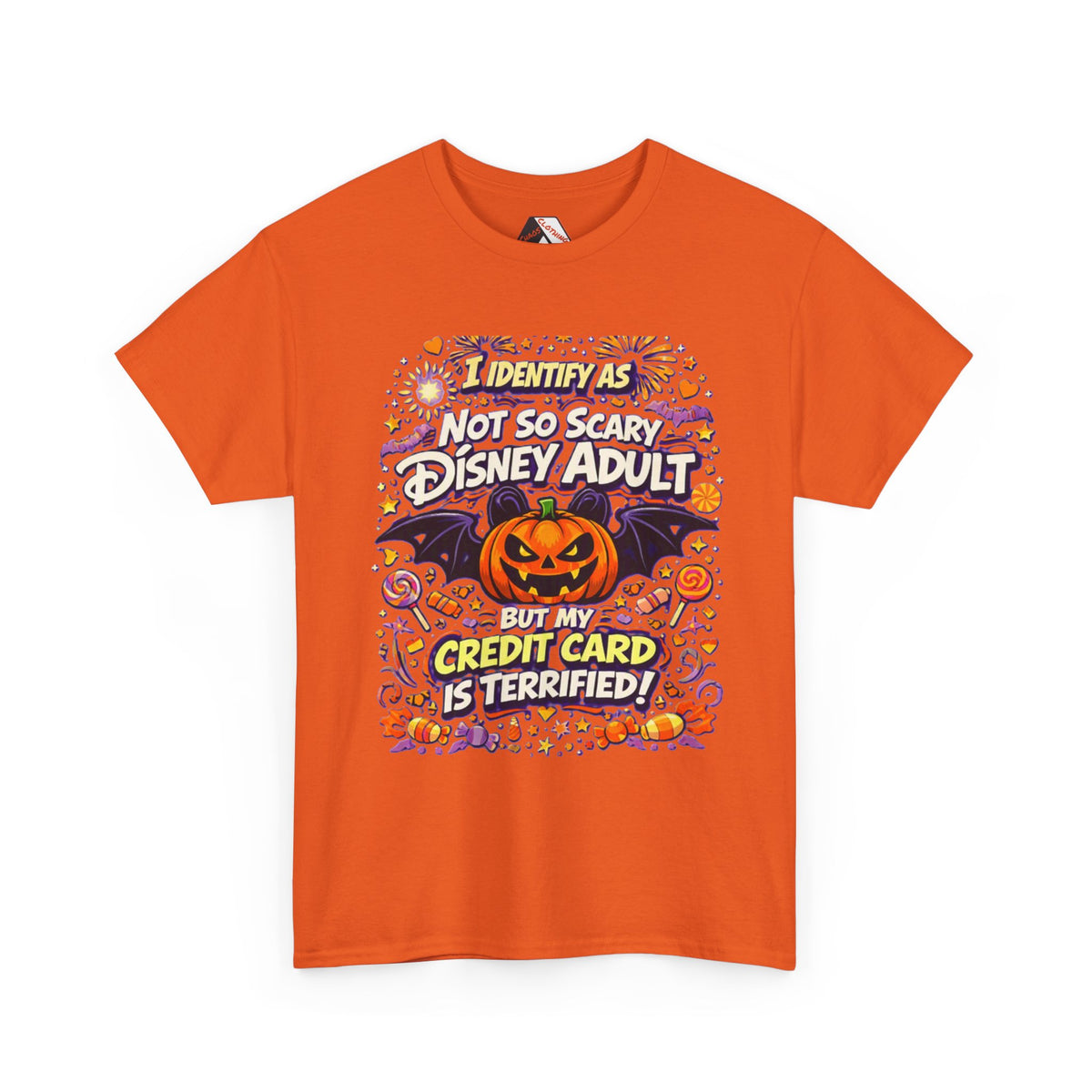An Orange short-sleeve crewneck t-shirt with a colorful graphic print on the front. The graphic features a jack-o'-lantern, bats, candy corn, and fireworks, with the text 'I IDENTIFY AS NOT SO SCARY DISNEY ADULT BUT MY CREDIT CARD IS TERRIFIED!' in stylized fonts.