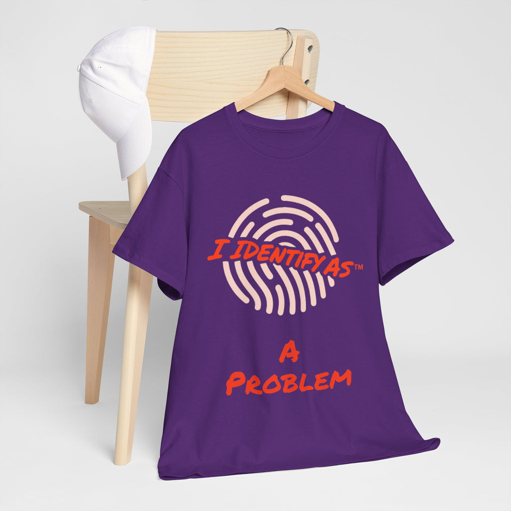 A purple short-sleeve t-shirt on a wooden hanger, styled in front of a light wood chair with a white cap. The shirt features a graphic of a fingerprint in light pink with the text 'I IDENTIFY AS' in orange , and 'A PROBLEM' in orange below.