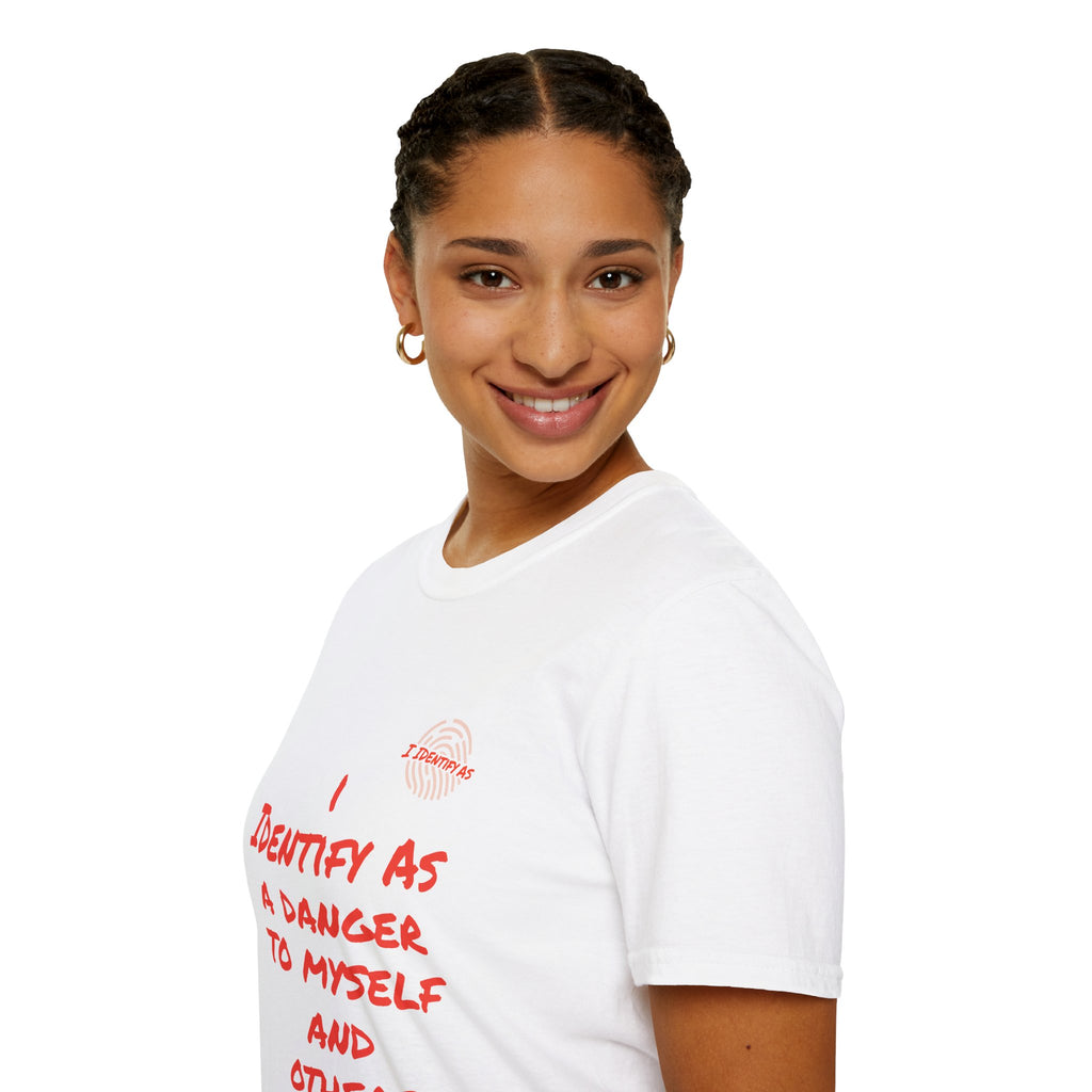 A smiling woman with braided hair is shown in a three-quarter profile wearing a white t-shirt with red text that reads 'I IDENTIFY AS A DANGER TO MYSELF AND OTHERS’ in a bold stacked font, with the I Identify As™ circular fingerprint logo printed above the text on the left chest.